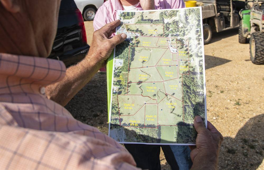 A producer's field plan held in weathered hands at the farm